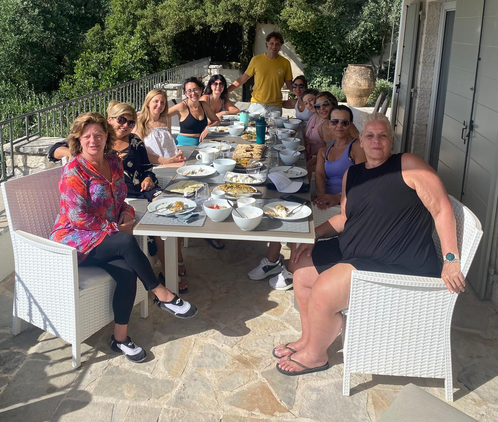 The retreat group gathered for breakfast at a long table on a stone terrace among olive trees